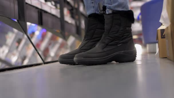 Shopaholic i nya svarta vinterskor står nära spegeln — Stockvideo