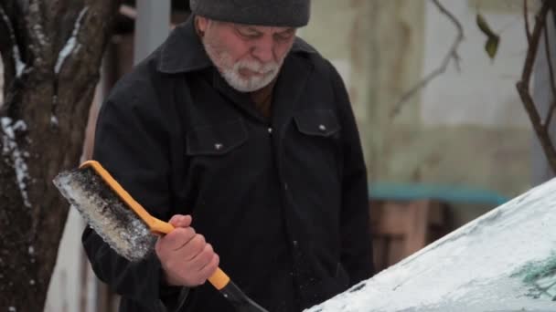 Vousatý senior muž čistí elektrický automobil čelní sklo — Stock video