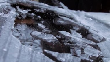 İnsan eli buz kazıyıcıyı tutar ve arabanın ön camını temizler.