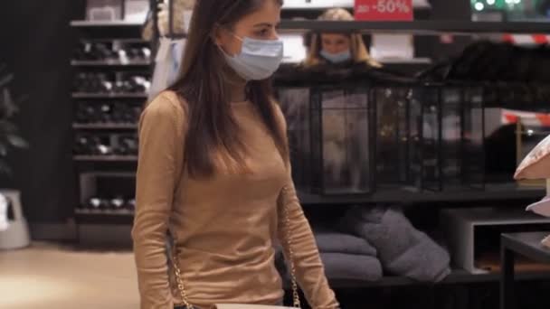 Lady i ansiktet mask promenader längs textila delen av butiken — Stockvideo