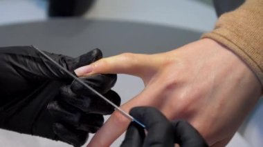 Profesyonel salon çalışanı, ziyaretçi çivilerini bir araçla dosyalar