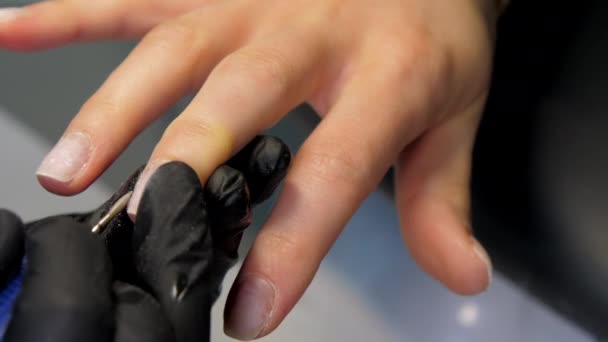 Beautician in gloves removes cuticle from woman fingernails — Stock Video