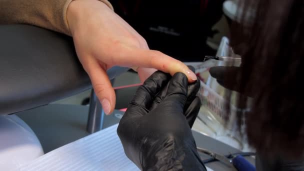 Beautician dalam sarung tangan steril menerapkan gel dasar pada kuku jari — Stok Video