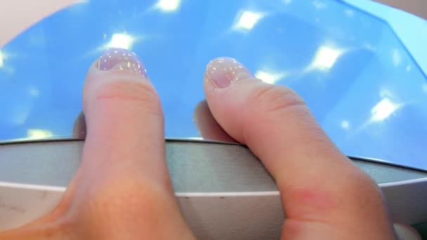 Kobieta suszy żel bazowy na paznokciach kciuka w świetle ultrafioletowym — Wideo stockowe