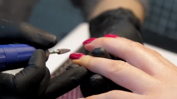 Geschoolde schoonheidsspecialiste in zwarte handschoenen hanteert rode manicure — Stockvideo