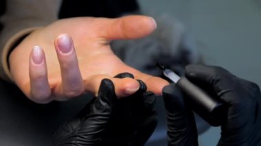 Deneyimli güzellik salonu çalışanı tırnaklarına jöle sürüyor.