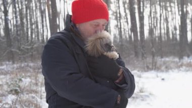 Sakallı emekli küçük bir köpek yavrusu tutuyor ve sarılıyor.