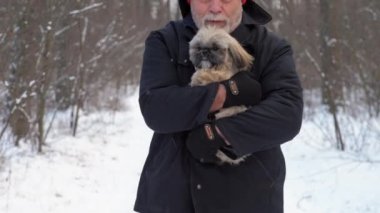Sakallı emekli küçük bir köpek yavrusu tutuyor ve sarılıyor.