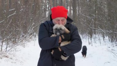 Kırmızı şapkalı yaşlı adam köpeği kollarına aldı ve ormanda yürüdü.