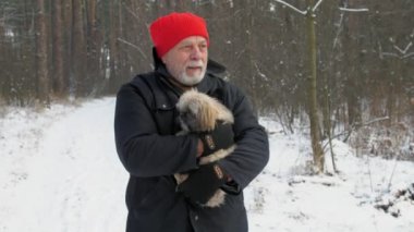 Sakallı yaşlı adam tüylü, titreyen köpeği kollarında tutuyor.