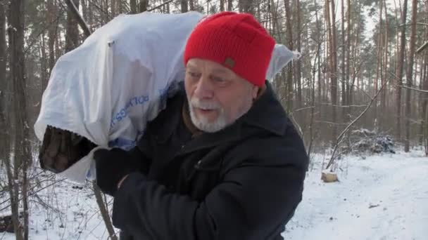 Homme âgé avec des promenades barbe grise tenant du bois de chauffage dans un sac — Video