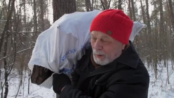 Homme âgé avec des promenades barbe grise tenant du bois de chauffage dans un sac — Video