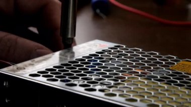 Adam elleri metal tornavidayla güç ünitesini söküyor.