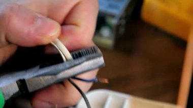 Tamirci metal penseyle beyaz ısı küçültücü boruları kesiyor.