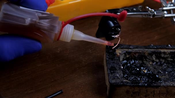 Opravář v rukavicích upustí tekutý pájecí tok na drát — Stock video