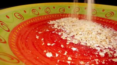 Lezzetli yulaf ezmesi kırmızı süslemeli sarı tabağa düşer.