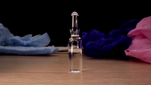 Injektionsflaska med genomskinlig vätska står på brunt träbord — Stockvideo