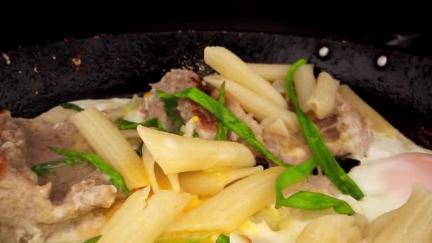 Pasta con huevos trozos de chuleta y cebolla verde yacen en la sartén — Vídeos de Stock