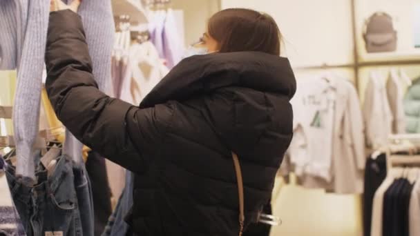 Молодая женщина в маске смотрит на белый пуловер размера — стоковое видео