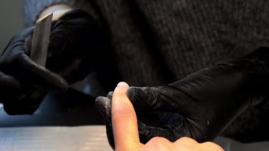 Eldivenlerdeki yetenekli güzellik uzmanı tırnaklarında manikür yapıyor.