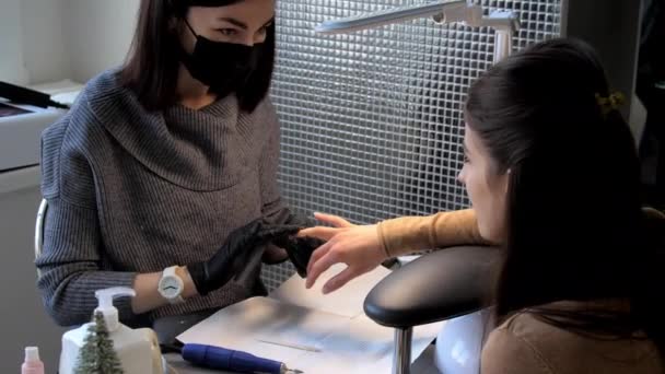 Salon werknemer in masker en handschoenen bestanden brunette vingernagels — Stockvideo