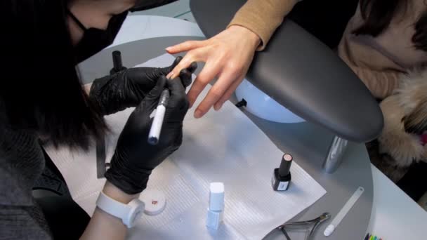Kosmetikerin trägt farbiges Gel auf Fingernägel auf — Stockvideo