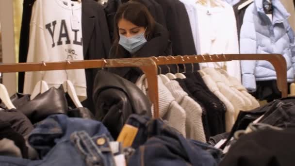 Lady in coat and face mask walks along department store — Stock Video