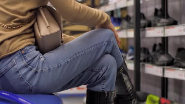 Mujer joven intenta negro zapato de invierno en la tienda en cámara lenta — Vídeos de Stock