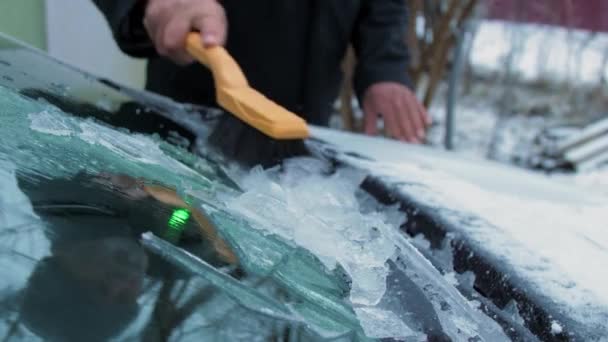 Рука старшої особи видаляє лід з автомобільного лобового скла — стокове відео