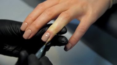 Güzellik salonu çalışanı tırnağına renkli jel sürüyor.
