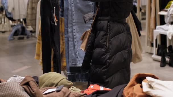 Young woman in black winter coat chooses colour of jeans — Stock Video