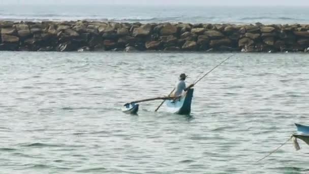 Азиатский рыбак с удочкой ловит рыбу в синей балансирующей лодке — стоковое видео