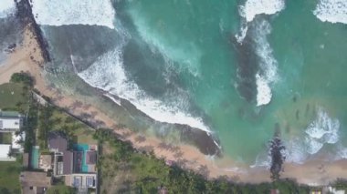 Okyanus ve binalar arasındaki sarı kumlu kıyı şeridi