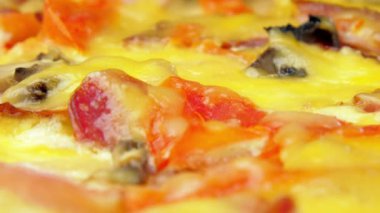 Pastırmalı pizza ve parlak ışık altında peynir.