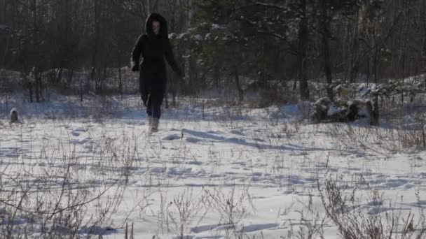 Ung kvinna i vinter rock i svart färg löper längs snö — Stockvideo