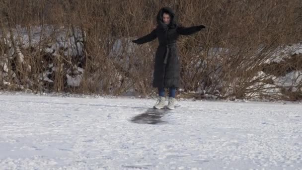 Młoda kobieta w długim zimowym płaszczu z czarnymi zjeżdżalniami — Wideo stockowe