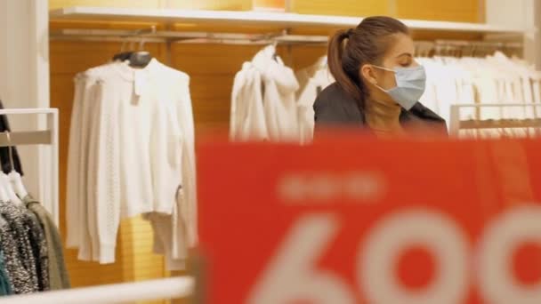 Lady wanders along store with clothes under discount signs — Stock Video