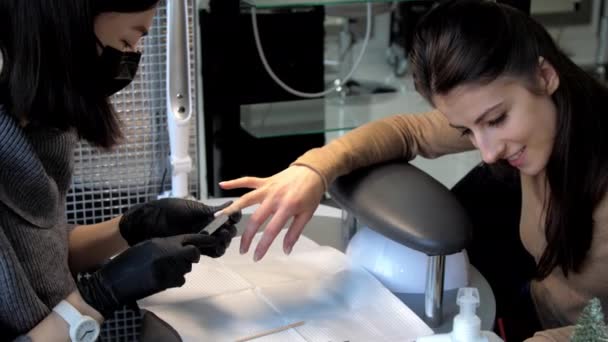 Manikérka v masce obličeje a rukavicích vytváří formu nehtů — Stock video