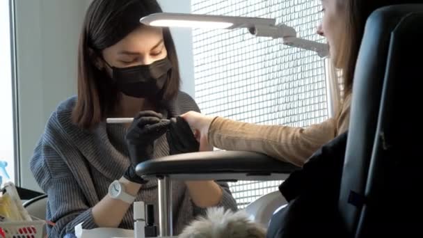 Manikiurzystka w masce i rękawiczkach kolory brunetka paznokcie — Wideo stockowe