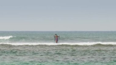 Ağ ile Asyalı balıkçılar okyanus dalgalarında duruyorlar.