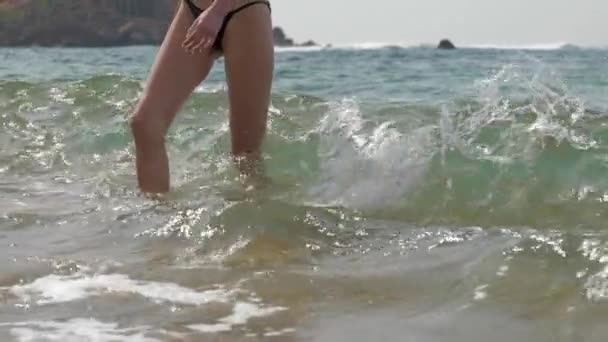 Szczupłe nogi pani chodzić wzdłuż brzegu morza z fal pluskających — Wideo stockowe