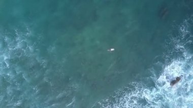 Sörfçü silueti gemide uzanıyor ve mavi okyanus boyunca yelken açıyor.