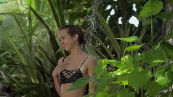 Bella donna gode di doccia esterna contro la flora tropicale — Video Stock