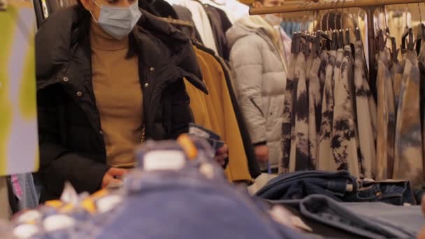 Junge Frau mit Einwegmaske hält gelben Pullover in der Hand — Stockvideo