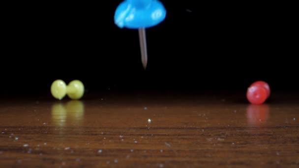 रंगीन प्लास्टिक धातु पिन ब्राउन लकड़ी की मेज पर गिरते हैं — स्टॉक वीडियो