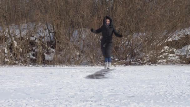 Young woman in long winter coat of black colour slides — Stock Video