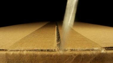 Manikürlü parmakları olan kişi büyük plastik kutuları keser.