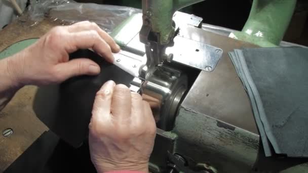Старые руки портного перемещать черные элементы кошелька кожи шитье — стоковое видео