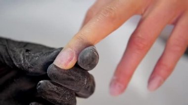 Steril eldivenli profesyonel manikürcü tırnaklarını törpülüyor.