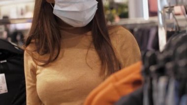 Tek kullanımlık maskeli kadın kot pantolon menziline bakıyor.